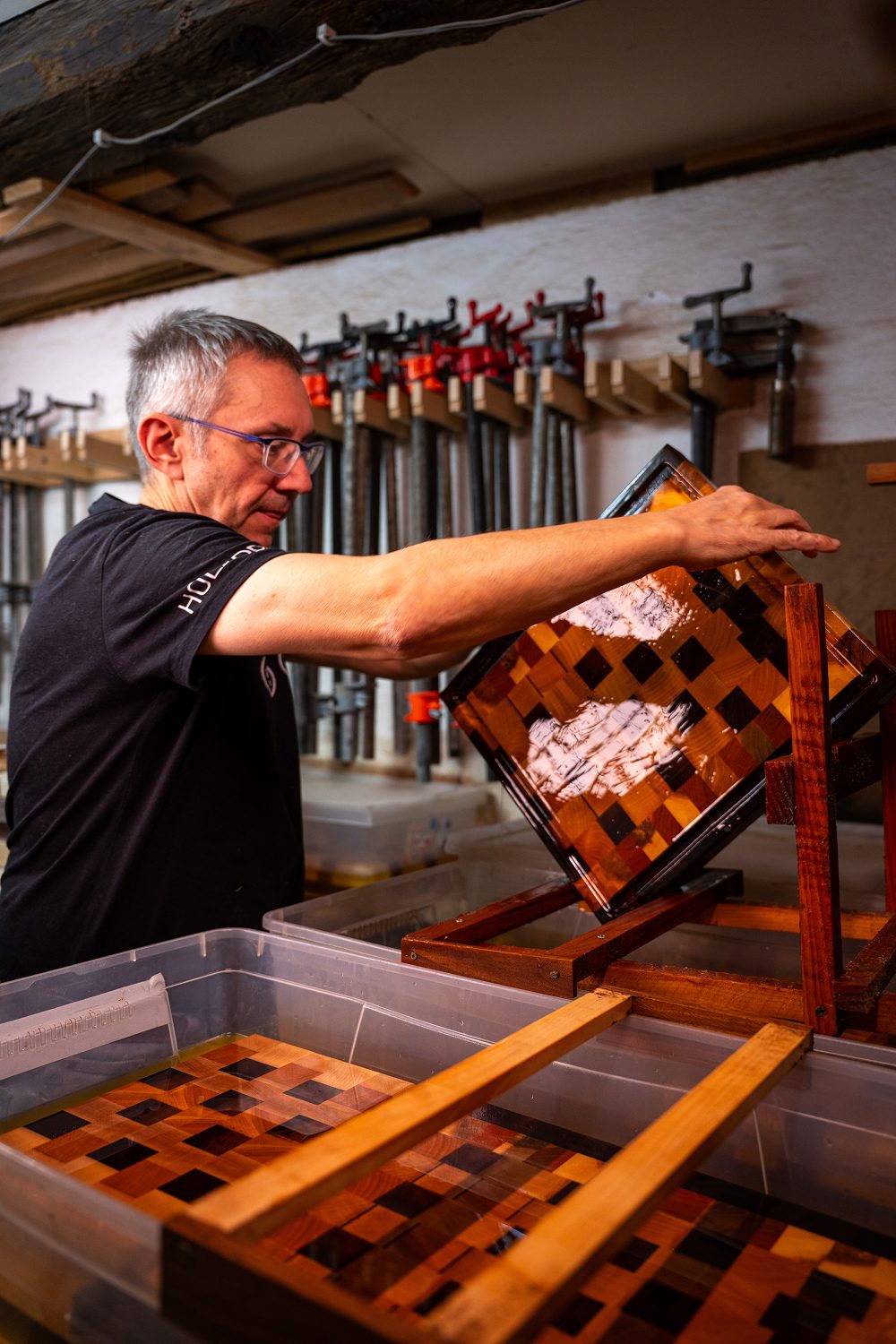 Homme inspectant une planche en bois vernissee.