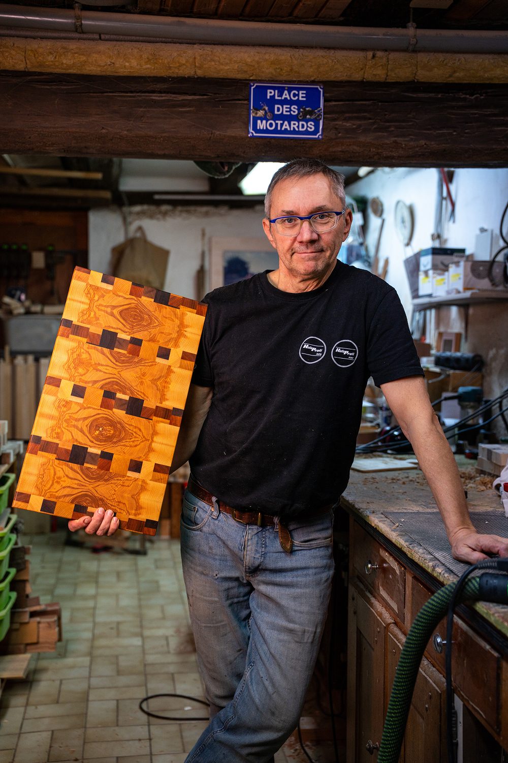 Homme tenant une planche a decouper en bois dans un atelier.