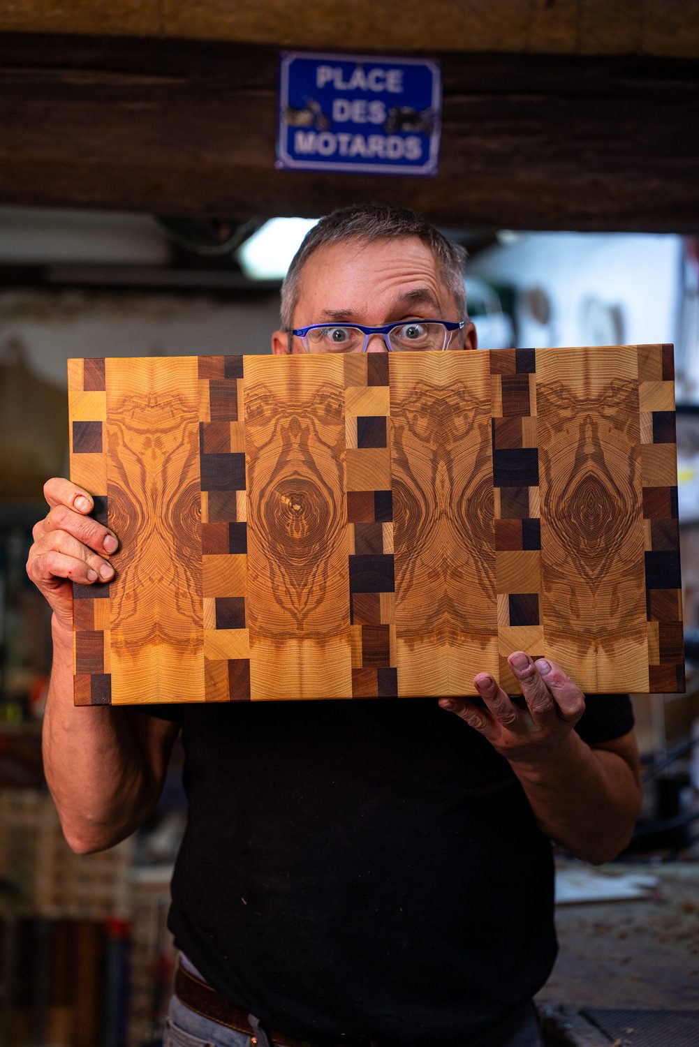Homme tenant une planche a decouper en bois symetrique.